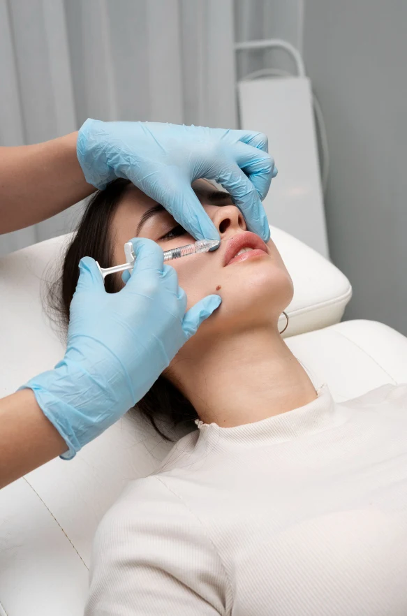 Mano de un médico inyectando suavemente la zona del arco de cupido durante un tratamiento de aumento de labios.