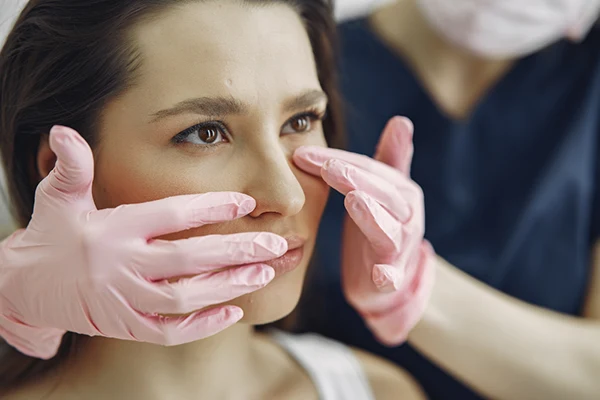 Médico examinando los surcos nasogenianos de una paciente durante la valoración facial.