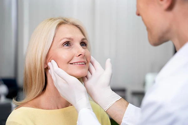Médico evaluando el tabique nasal de una paciente durante una valoración estética.