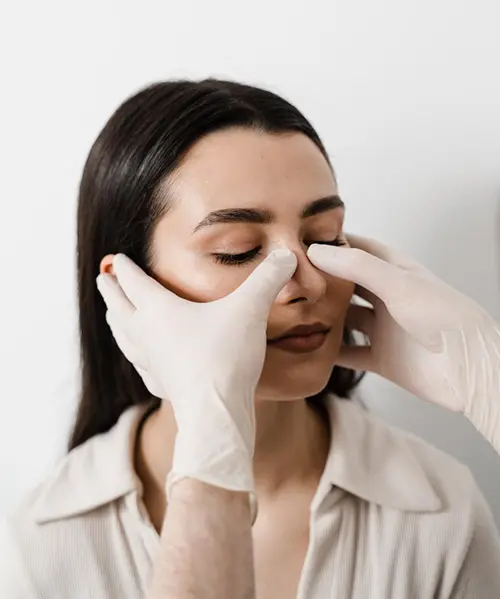 Médico evaluando el tabique nasal de una paciente durante una valoración estética.