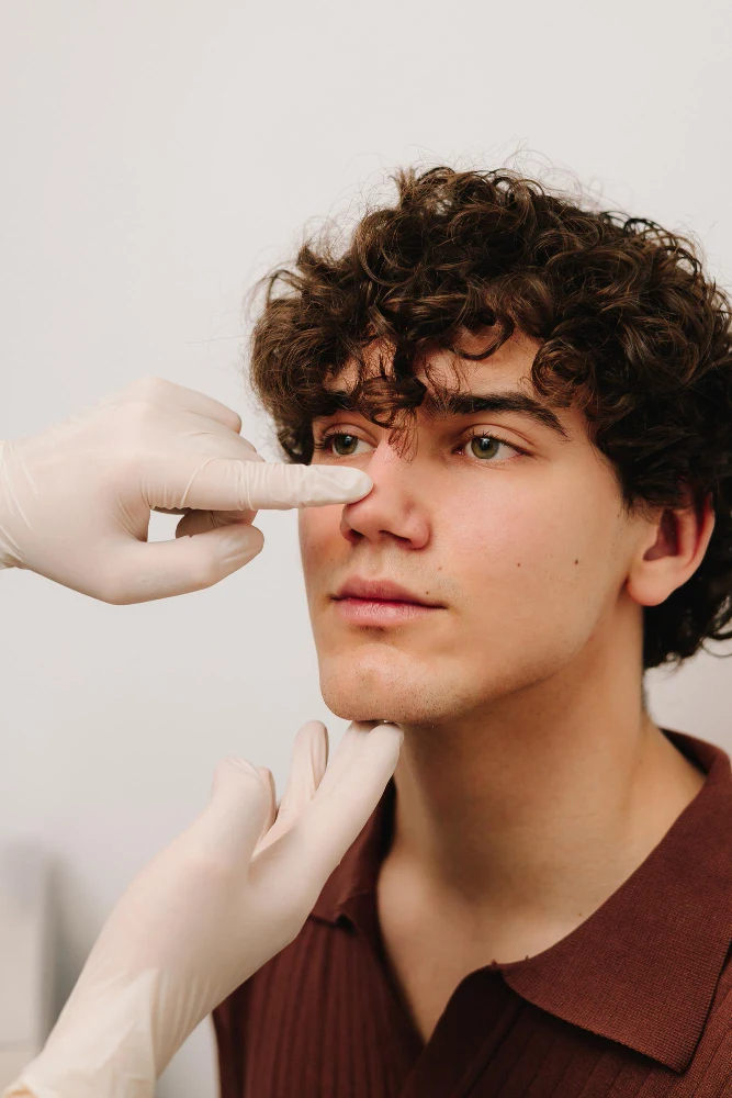 Médico evaluando la nariz de una paciente durante una valoración de rinomodelación.