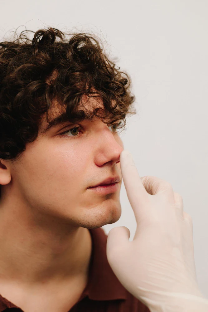 Médico evaluando el tabique nasal de una paciente durante una valoración estética.